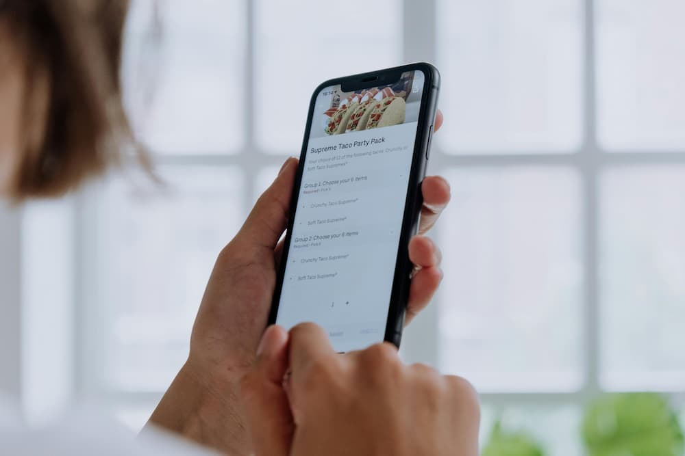 Una mano sosteniendo un teléfono inteligente que muestra en la pantalla un menú de comida digital.