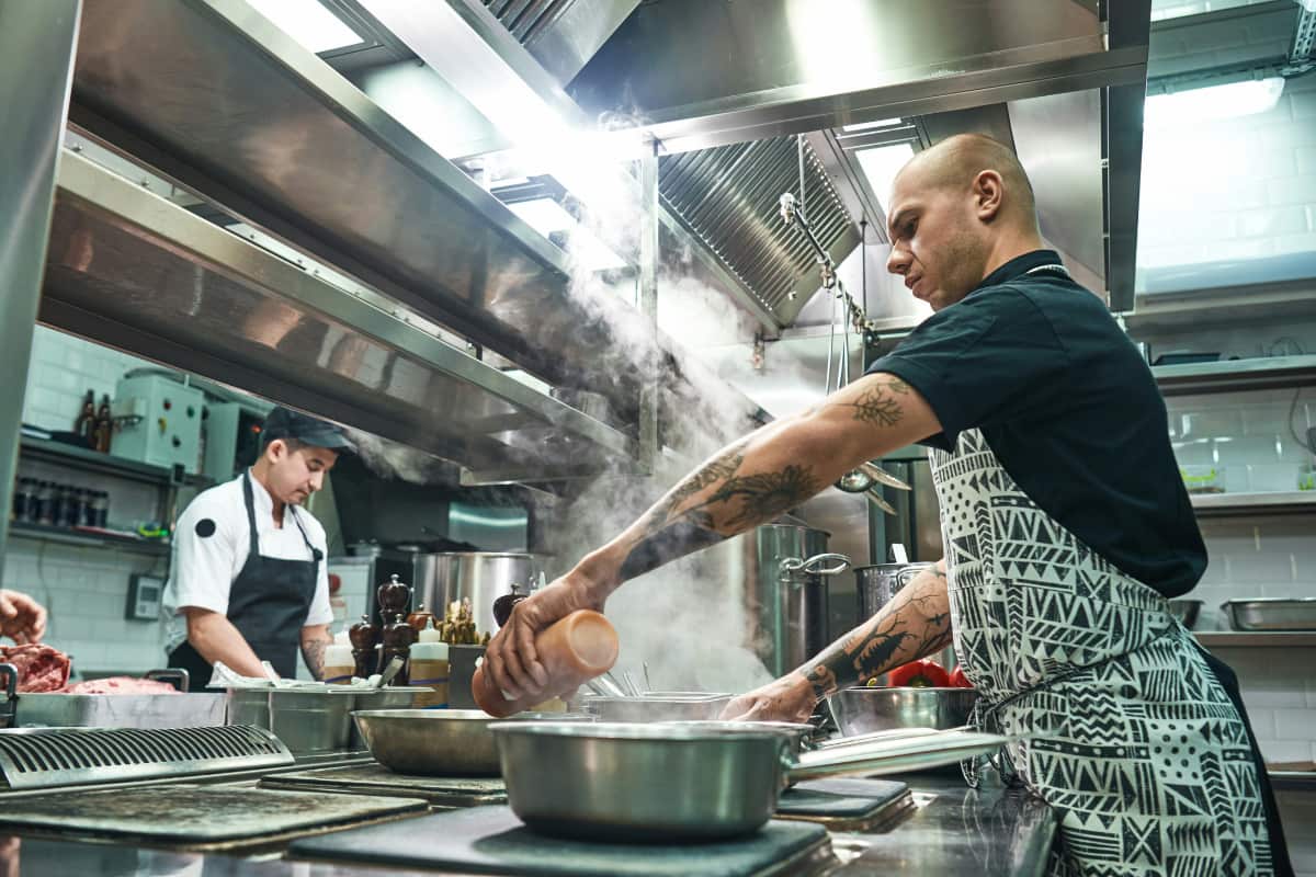 Cozinheiros trabalhando em uma cozinha industrial, mostrando como montar uma dark kitchen eficiente e bem equipada.