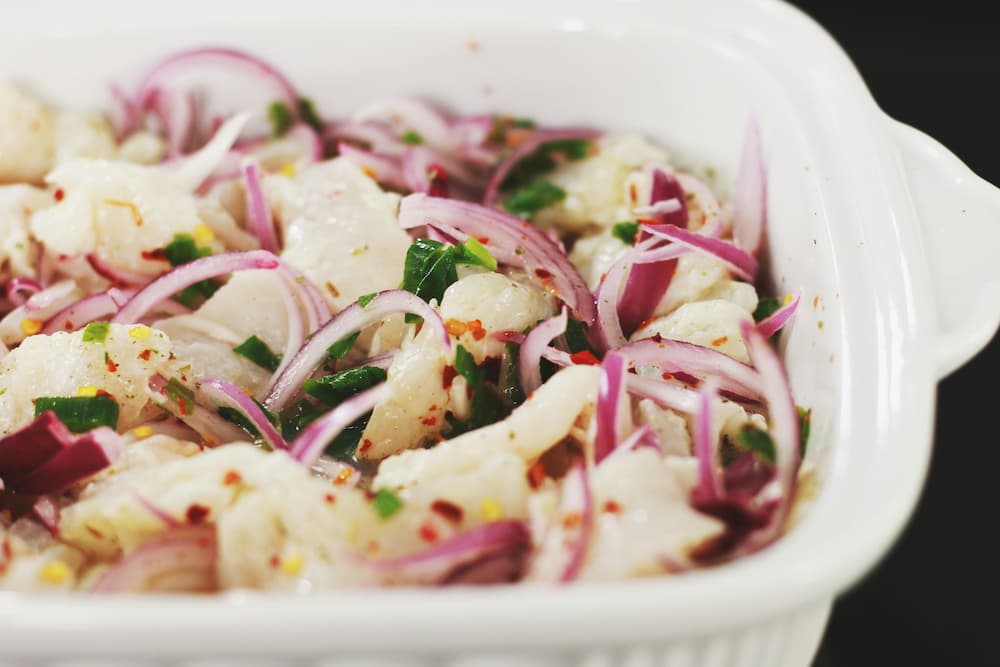 El ceviche está compuesto por trozos de pescado crudo marinados en jugo de limón, mezclados con cebolla morada, ají, y cilantro. Un símbolo icónico de la rica gastronomía peruana.