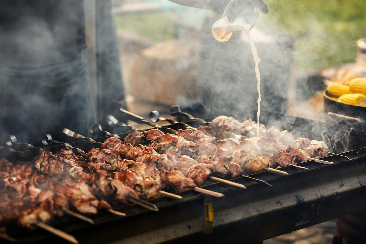 Churrasco sendo preparado na grelha com espeto, ilustrando dicas sobre como montar um delivery de churrasco de sucesso.