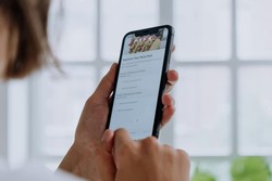 Una mano sosteniendo un teléfono inteligente que muestra en la pantalla un menú de comida digital.