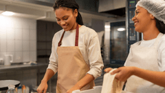 Esta imagem retrata um momento de colaboração e alegria entre duas cozinheiras jovens.