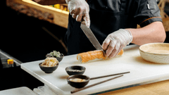 Esta imagem foca em um chef jovem e focado em sua tarefa, preparando sushi.