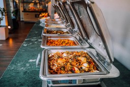 Buffet de comida quente com diversas opções, ilustrando a diferença entre catering e buffet na organização de eventos.