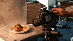 Os bastidores de um ensaio fotográfico de alimentos em um estúdio improvisado ou técnico.