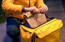 Entregador tira o pedido de sua bolsa com cuidado apos descobrir O que não pode faltar em um delivery