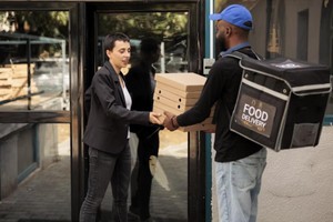 Repartidor entregando cajas de comida a cliente, ilustrando los tiempos de entrega en dark kitchen en zonas residenciales.